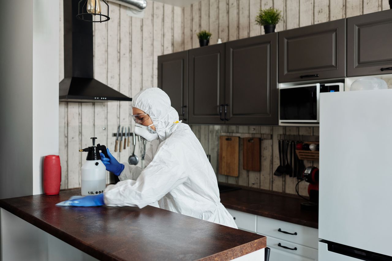 Un intervenant en tenue de protection désinfecte une cuisine, afin de garantir un environnement propre et sûr.